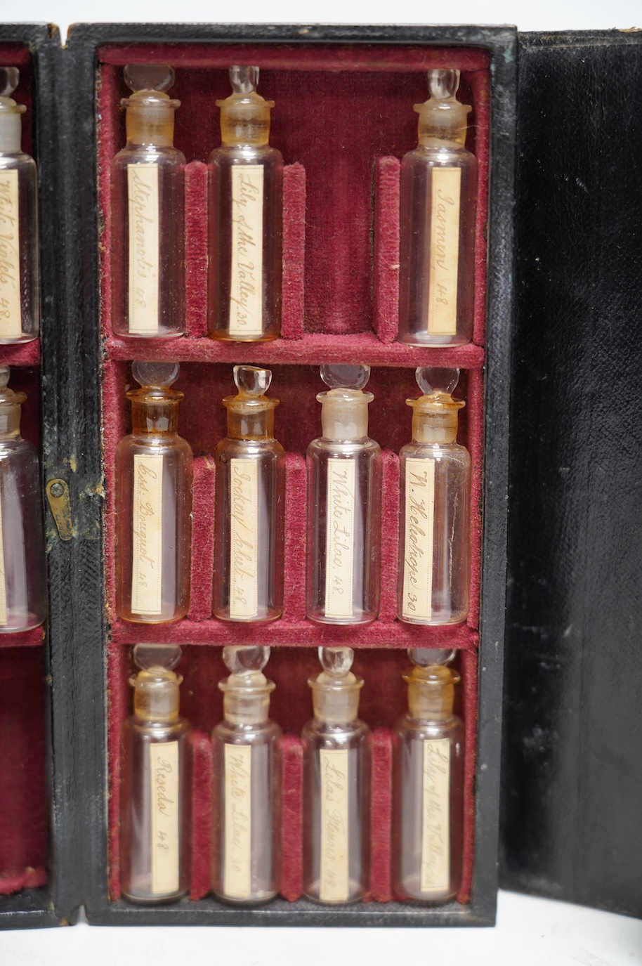 A late 19th century leather cased perfume or apothecary set by Lynch & Co., containing seventeen miniature bottles with old labels, (seven bottles missing), 20.5cm x 10cm x 4.5cm. Condition - fair